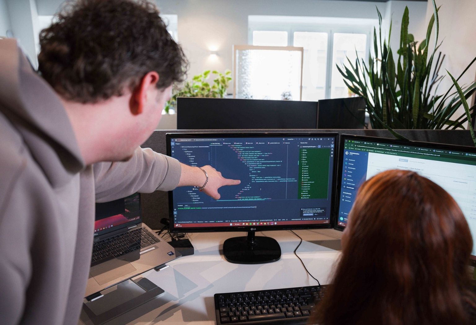Ein Mann und eine Frau sitzen an einem Tisch und nutzen einen Computer, um an einem Projekt zu arbeiten.