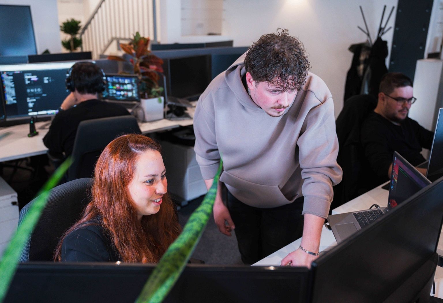 Zwei Personen arbeiten konzentriert an Computern in einem modernen Büro.